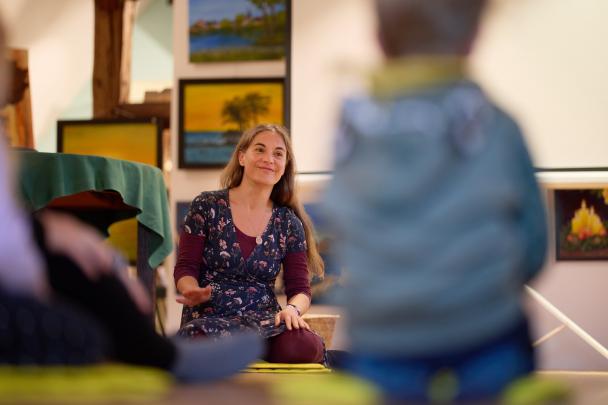 eine Frau sitzt auf dem Boden und musiziert mit Kindern