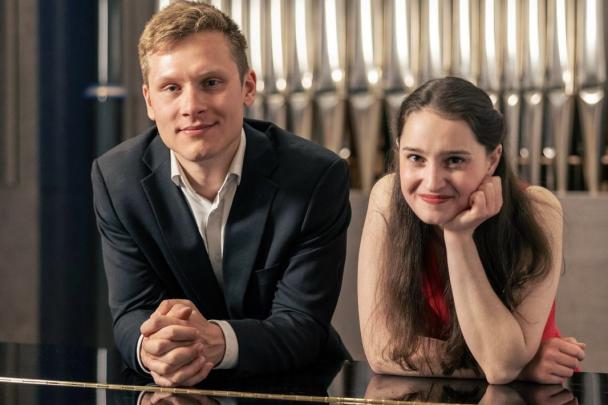 zwei junge Menschen schauen über einen Flügel