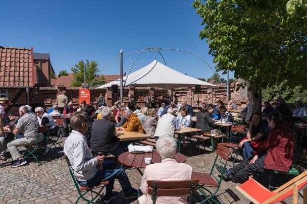 Menschen sitzen im Sonnenschein auf dem Museumshof