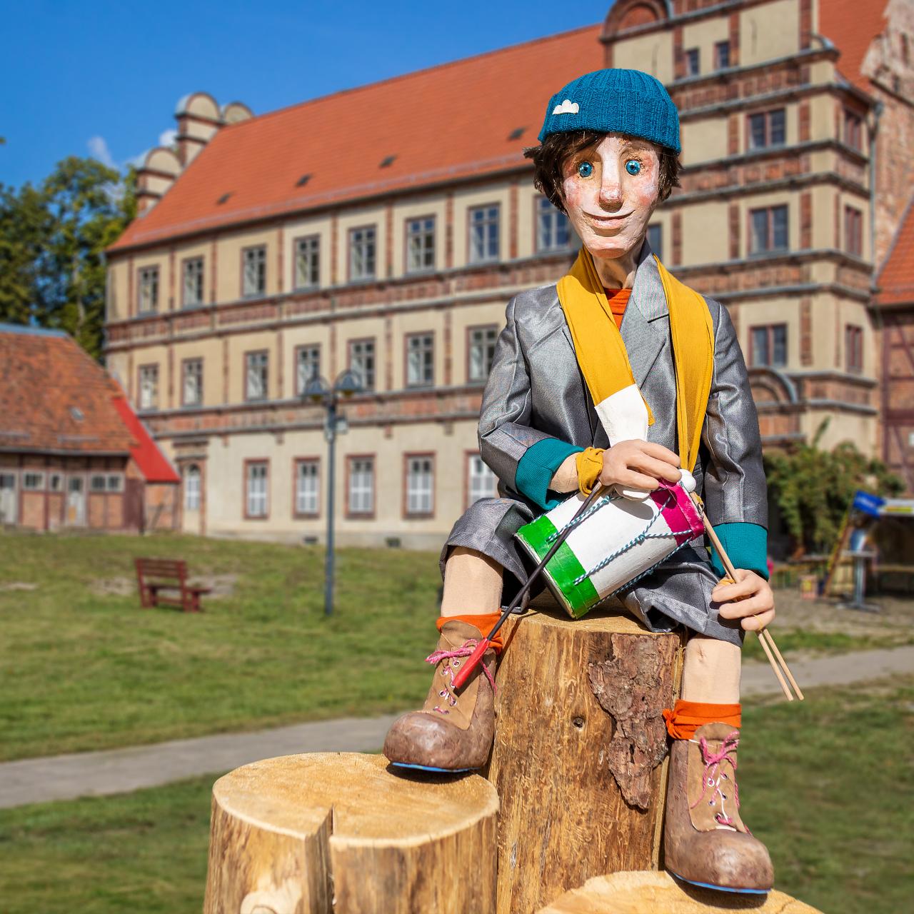 Tromino sitzt auf Baumstämmen vor dem Schloss