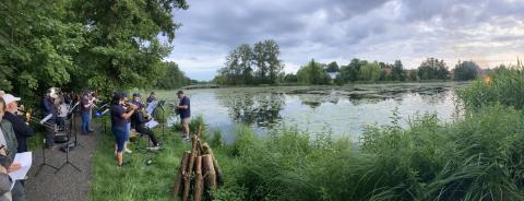 Ein Musikensemble steht am Ufer des Burgsees und Musiziert