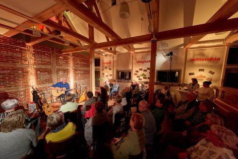 Ein Gitarrist spielt vor Publikum in gemütlicher Atmosphäre