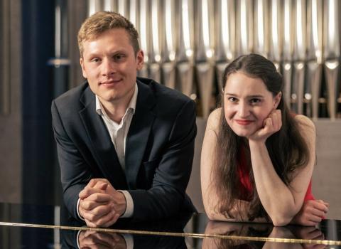 zwei junge Menschen schauen über einen Flügel