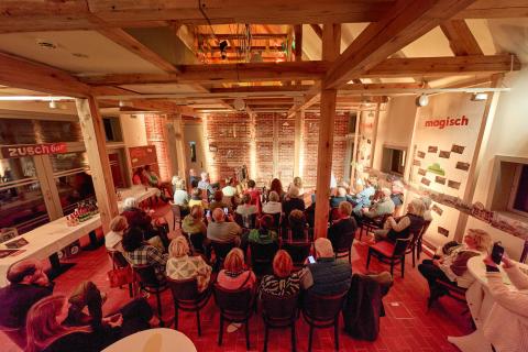 Ein Publikum sitzt in der Remise und schaut zur Bühne.